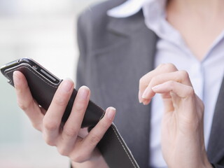 Woman is holding a cell phone in her hand while wearing a suit