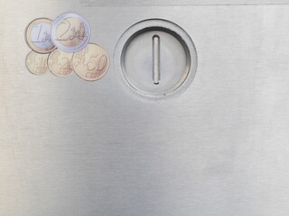 Silver coin slot with a coin in it and a bunch of coins on top of it
