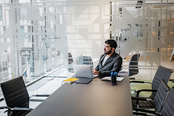 A dedicated and focused professional is attentively working at a contemporary office desk, surrounded by advanced technology