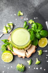 Green smoothie with broccoli lime and basil leaves on dark background