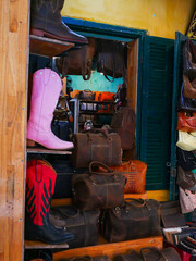 Western-style cowboy boots in red, pink, black contrast with wide selection of rugged leather bags...