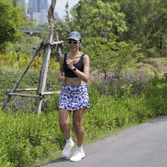 Fit Asian female wearing black sports bra and a patterned skort doing her morning running routine...