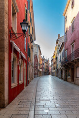 Empty cobblestone street in colorful European town. Curved cobblestone street lined with colorful, historic buildings in a charming European town, captured in quiet early morning light.