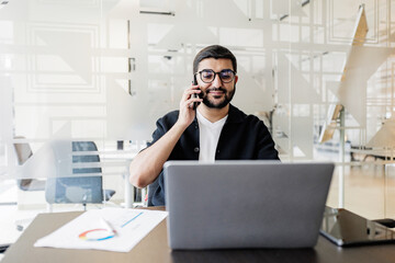 Professional man engages in a business call while working at a stylish desk in a modern office...
