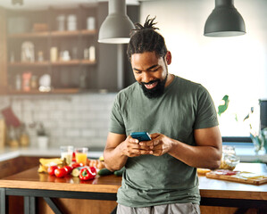Happy young afro american man having fun preparing food and looking for recipes online using a...
