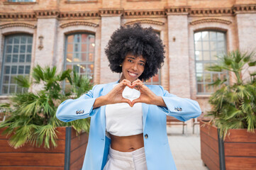 Young manager showing heart with hands in front of office building