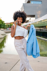 Businesswoman smiling and talking on phone while holding jacket