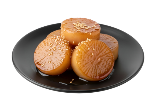 A plate of caramelized daikon radish slices, garnished with sesame seeds, sits on a dark plate against a black background.