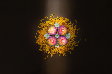 Four Diwali candles arranged with marigold petals for celebration