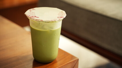 Iced matcha latte in a plastic cup on the table