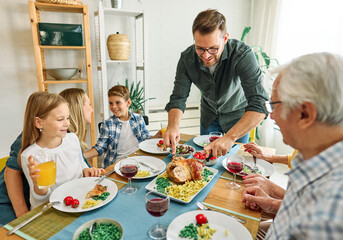 Happy multi-generation family gathering around dining table and having fun during a lunch or dinner...