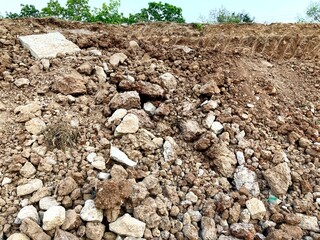 A close-up view of rocky soil with scattered stones and uneven terrain, suitable for construction, geology, or nature concepts