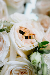  Gold wedding ring placed inside ivory rose bouquet, romantic macro floral detail.
