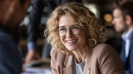 Smiling mature businesswoman in glasses during office meeting. Concept of leadership, professional success, career growth, negotiation, teamwork, executive confidence and corporate collaboration.