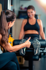 Thumbs up, personal fitness coach encourages a smiling female client in a gym training