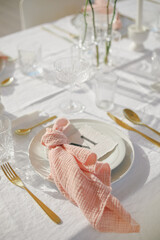  Elegant wedding table setting with glassware, plates and pink napkins.