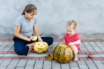 Fototapeta premium Mother and daughter carving pumpkins for halloween party