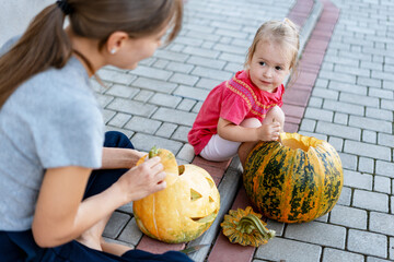 Fototapeta premium Mother and daughter carving pumpkins for Halloween party