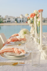 Elegant outdoor wedding table setup with ocean view background.