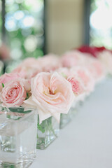 Beautiful wedding table decorated with pink roses in glass vases.