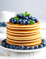 Stack of golden pancakes topped with blueberries and mint