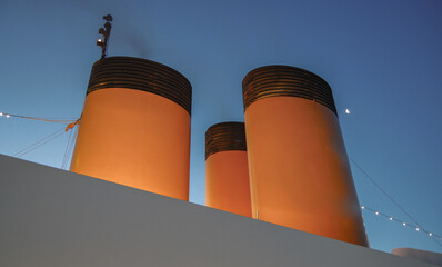 Yellow and black painted funnel smoke stack of luxury cruiseship cruise ship liner against blue sky