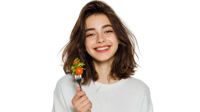 Smiling woman holding a fork with fresh vegetable salad in a bright setting.