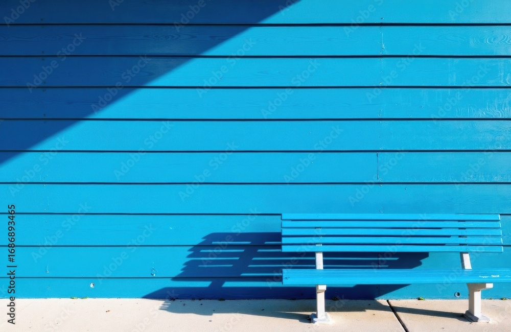 Poster a blue wooden wall with a shadowed bench creating geometric patterns and visual depth