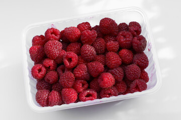 Fresh raspberries in a clear container ready for culinary delight or healthy snacking