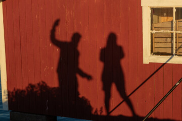 Two playful shadows on a wooden wall. Creative abstract outdoor scene symbolizing joy, friendship,...