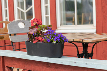 Flower pot on the railing of a rustic Finnish wooden cafe. Simple countryside lifestyle, summer...