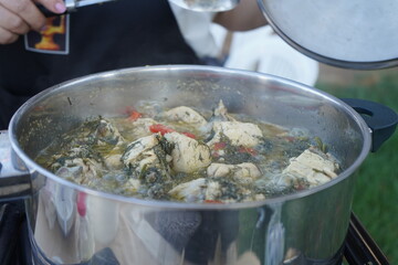 A close-up shot of traditional Cretan chicken with fennel simmering in a pot, showcasing the rich...