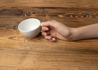 Hand Holds Cup, Empty White Cup in Hands, Coffee Mug, Teacup Mockup, Cup in Arms on Wooden Table