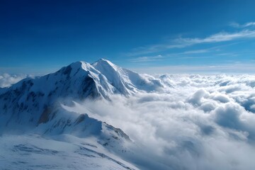 Fototapeta premium Snow-covered peak towering above clouds.