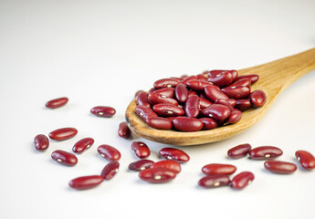 Red bean seeds on a wooden spoon on a white background