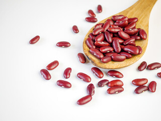 Red bean seeds on a wooden spoon on a white background