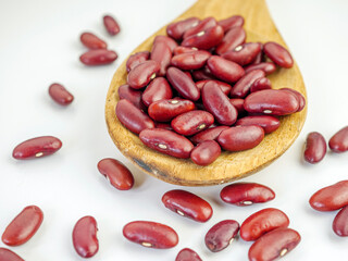Red bean seeds on a wooden spoon on a white background