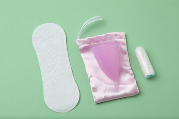 feminine pads, tampons, menstrual cup feminine hygiene products on a green background
