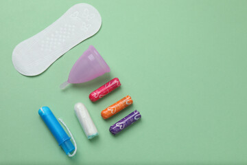 feminine pads, tampons, menstrual cup feminine hygiene products on a green background
