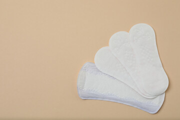 feminine pads, tampons, menstrual cup feminine hygiene products on a beige background
