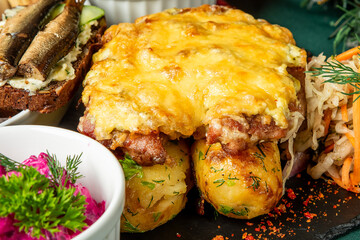 Traditional Eastern European meal with baked potatoes, beet salad, rye bread with fish, and sauerkraut, served on a rustic slate platter with fresh herbs and seasoning