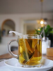 Mug of tea with a tea bag in it sits on a white plate