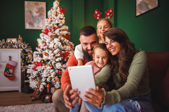 Family having fun taking selfies by the Christmas tree - Powered by Adobe