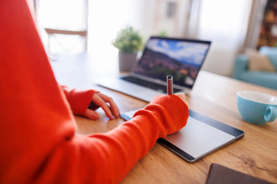 Graphic designer drawing using drawing pad while working remotely from home - Powered by Adobe