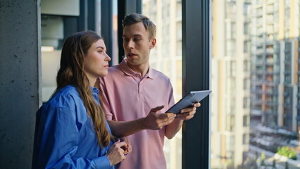 Couple colleagues discussing strategy talking at panoramic window office closeup