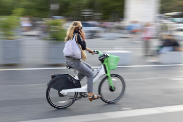 Young Woman Riding Bicycle While Talking on Mobile Phone Outdoors