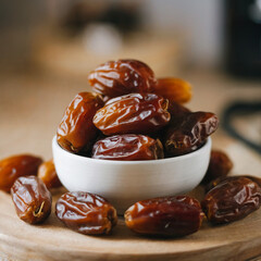 Dried dates in a white bowl on a wooden surface