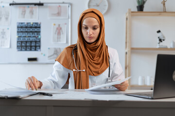 Arab female doctor reading document making paperwork working in the clinic