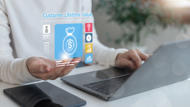 Businesswoman using a laptop with a digital hologram showing Customer Lifetime Value CLV. Concept of customer retention, loyalty, business KPI, revenue growth, and marketing strategy analytics.