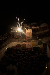 Festive Sparkler with Cake and Sweets in Dark Atmosphere